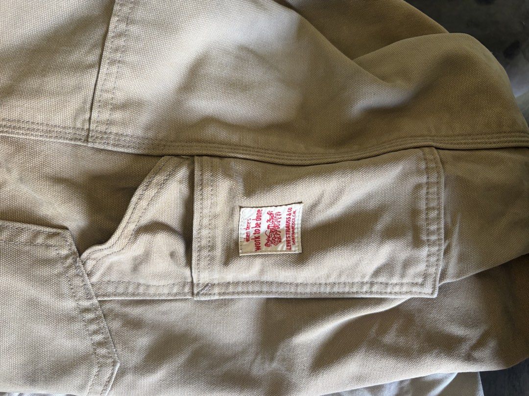 Levi's Canvas Utility Work Pants Beige Distressed Knees (Category: Jeans) located in Taytay. Submitted by newphoenix.31abd6 (Listing ID 1465588407, Image 3). Description: - Brand: Levi's - Color: Tan - Style: Utility work pants / carpenter style with relaxed straight leg - Details: Double knees with distressing, side utility pockets, and iconic red tab - Special Feature: Inner pocket lining features Levi's 150 years text print - Material: Durable