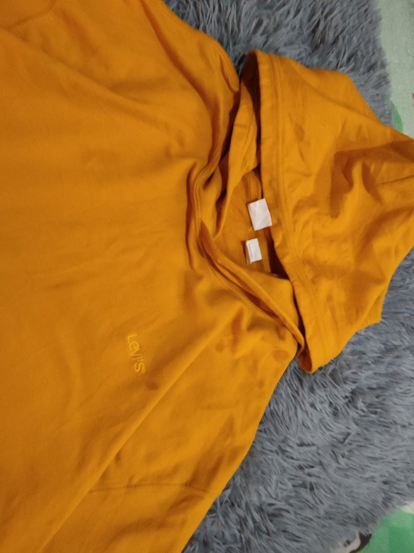 Levi's Yellow Hoodie (Category: Hoodies) located in Manila. Submitted by mommyregsthriftclothes (Listing ID 1465642188, Image 2). Description: - Brand/Style: Levi's hoodie in a bright mustard yellow color - Details: Embroidered Levi's logo on the chest, front kangaroo pocket, and soft fleece interior - Condition: Shows visible staining and discoloration spots on the front pocket and lower body area - Fit/Sizing: Exact measurements are shown with 