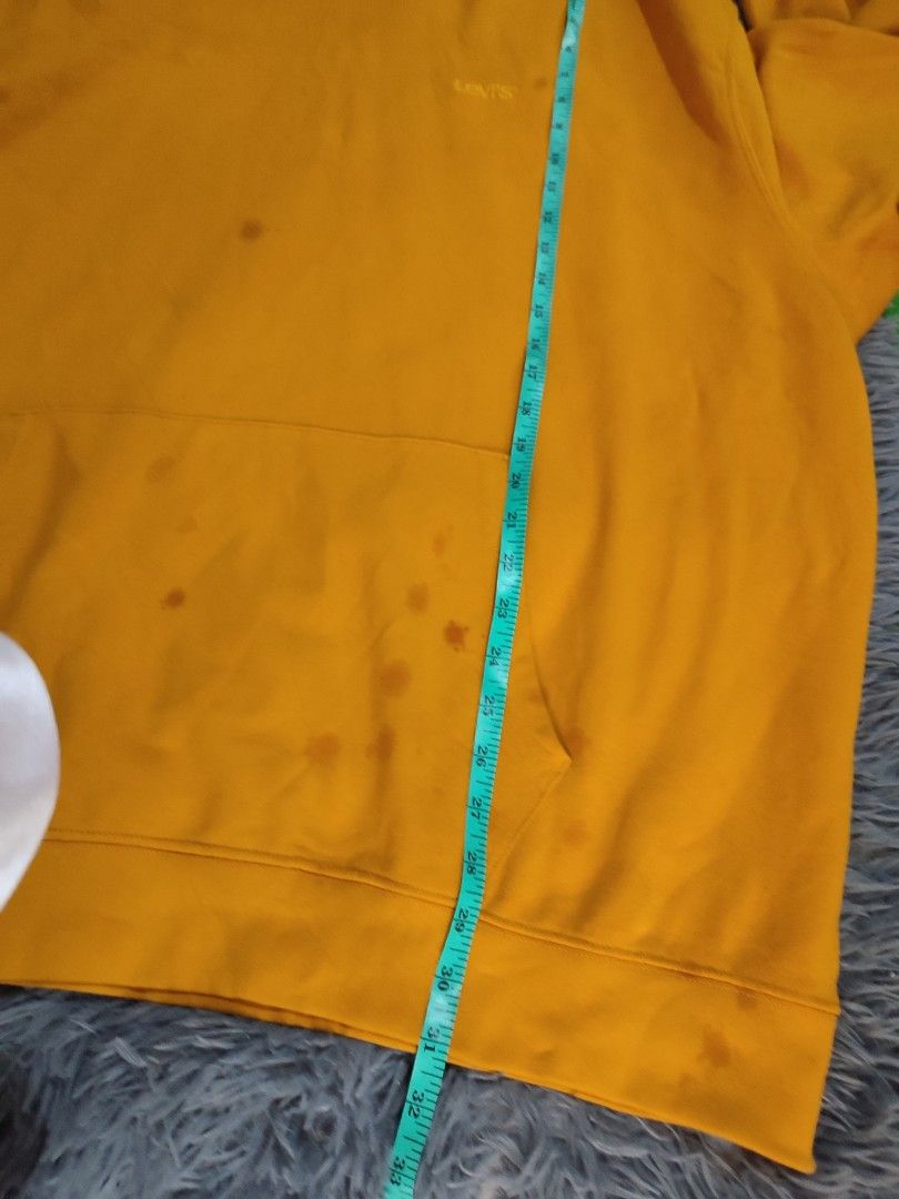 Levi's Yellow Hoodie (Category: Hoodies) located in Manila. Submitted by mommyregsthriftclothes (Listing ID 1465642188, Image 3). Description: - Brand/Style: Levi's hoodie in a bright mustard yellow color - Details: Embroidered Levi's logo on the chest, front kangaroo pocket, and soft fleece interior - Condition: Shows visible staining and discoloration spots on the front pocket and lower body area - Fit/Sizing: Exact measurements are shown with 