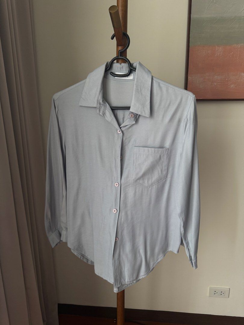 Light blue long-sleeve button-down collared shirt (Category: Longsleeves) located in Pasig City. Submitted by kutleyn (Listing ID 1465655255, Image 1). Description: - Color: Light blue with contrast pink buttons - Style: Long-sleeve shirt with classic pointed collar and curved hem - Details: Single patch pocket on the left chest - Fabric: Soft with a nice drape - Condition: Clean, no obvious flaws - Versatility: Great basic piece for layering or 