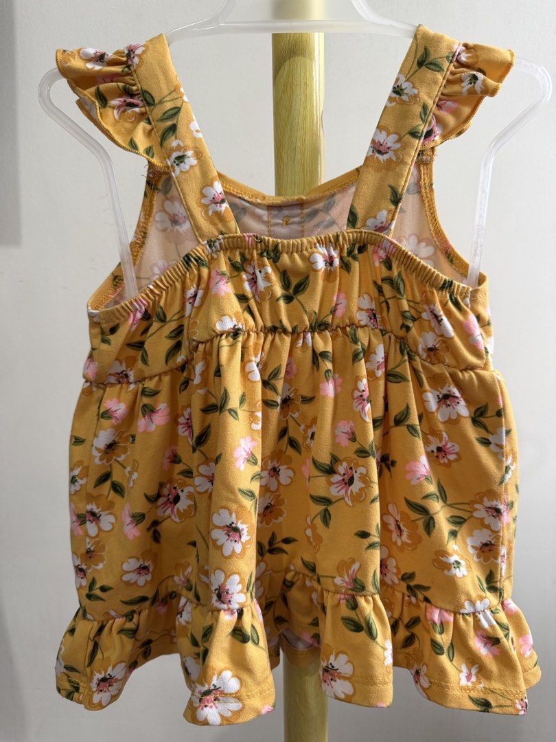 Little Lass Yellow Floral Top (Category: Babies & Kids Fashion) located in Quezon City. Submitted by warmrabbit_414908 (Listing ID 1465597191, Image 3). Description: - Brand: Little Lass - Design: Yellow with white/pink flowers and green leaves - Features: Ruffle shoulder straps, functional front buttons, gathered waist, and flared ruffled hem - Condition: Brand tag attached inside neckline - Material: Lightweight and comfortable for toddlers.