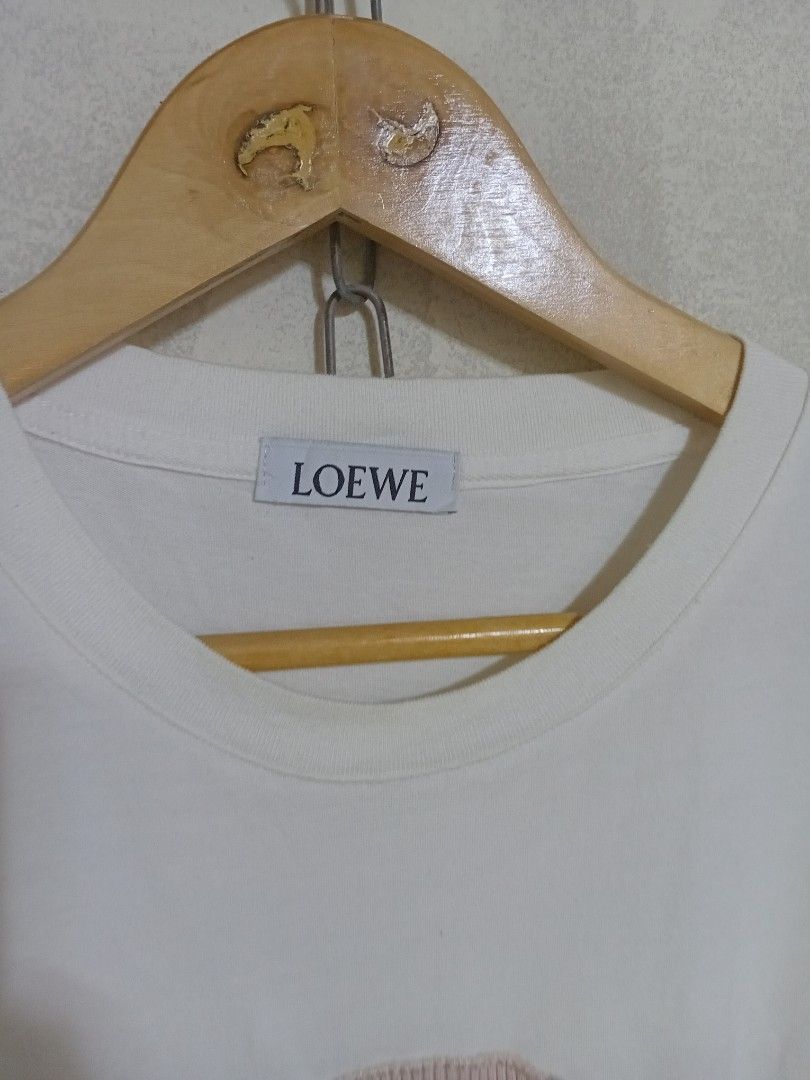 LOEWE White Graphic Embroidered T-Shirt (Category: Shirts) located in San Jose del Monte. Submitted by dripfromthrift2 (Listing ID 1465579396, Image 3). Description: - Brand: Loewe - Color: White with pale pink, grey, and black abstract face embroidery - Fit: Classic relaxed fit with a clean crew neckline - Material: Soft, premium cotton - Condition: Excellent / Like new - Style: Versatile everyday basic with unique designer detailing.