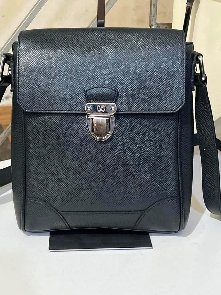 Louis Vuitton Taiga Leather Messenger Bag (Category: Sling Bags) located in Quezon City. Submitted by luxuriesbymichiika (Listing ID 1465707855, Image 1). Description: - Brand: Louis Vuitton - Material: Premium Black Taiga leather - Closure: Secure metal push-lock with iconic LV logo - Strap: Adjustable shoulder strap with silver-tone hardware - Design: Structured flap with reinforced corner panels and clean stitching - Use: Practical and stylish