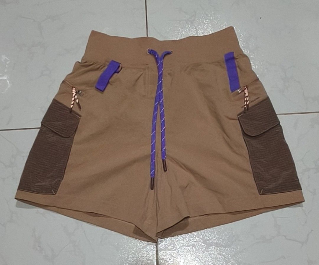 Lululemon Multi-Pocket Hiking Shorts Brown Size 4 (Category: Shorts) located in Pili. Submitted by fiercestorm.fcba92 (Listing ID 1465690310, Image 1). Description: - Brand: Lululemon - Style: Hiking shorts - Color: Tan and brown with purple drawstring accents - Size: 4 (170/64A) - Material: Recycled nylon and elastane (tag attached) - Features: Large cargo pockets on both sides, zipper details, and small gear loops.