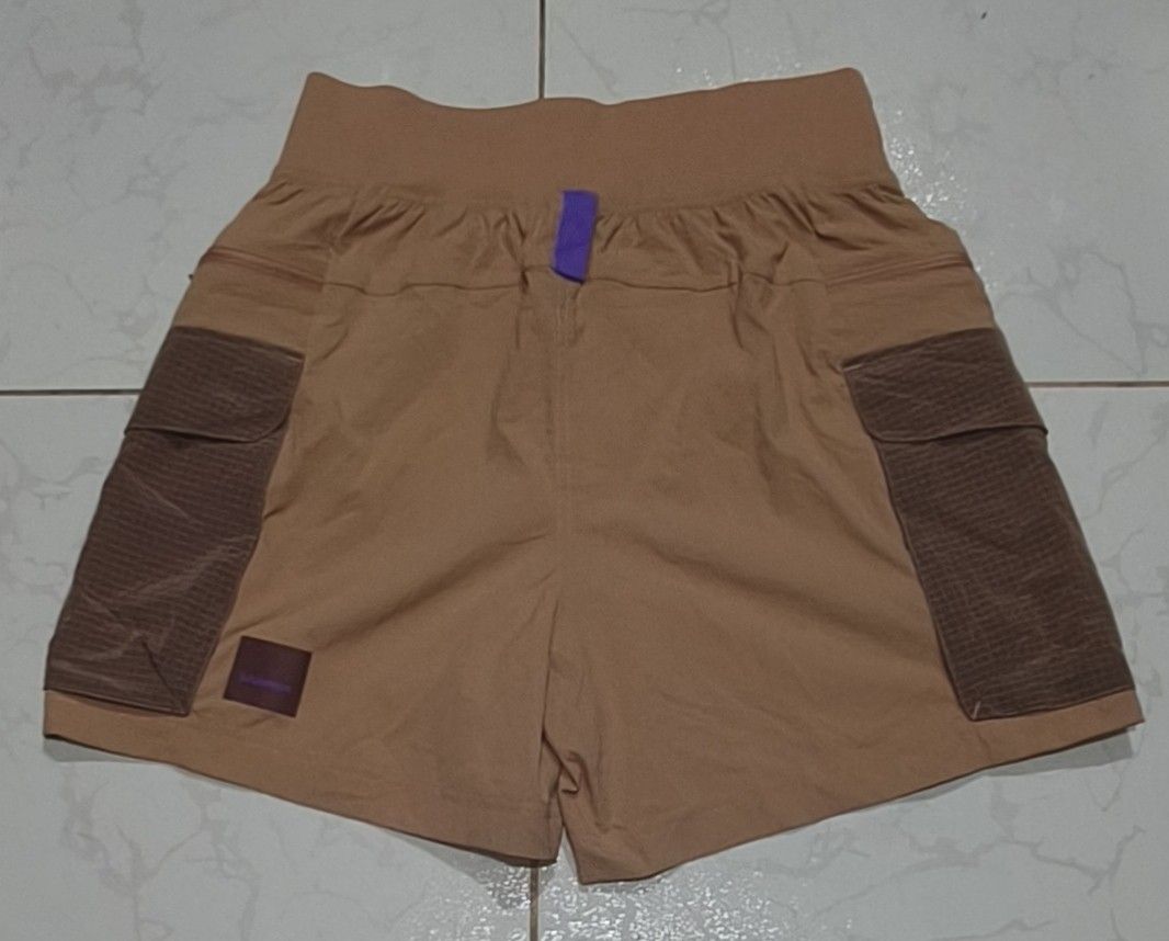 Lululemon Multi-Pocket Hiking Shorts Brown Size 4 (Category: Shorts) located in Pili. Submitted by fiercestorm.fcba92 (Listing ID 1465690310, Image 2). Description: - Brand: Lululemon - Style: Hiking shorts - Color: Tan and brown with purple drawstring accents - Size: 4 (170/64A) - Material: Recycled nylon and elastane (tag attached) - Features: Large cargo pockets on both sides, zipper details, and small gear loops.