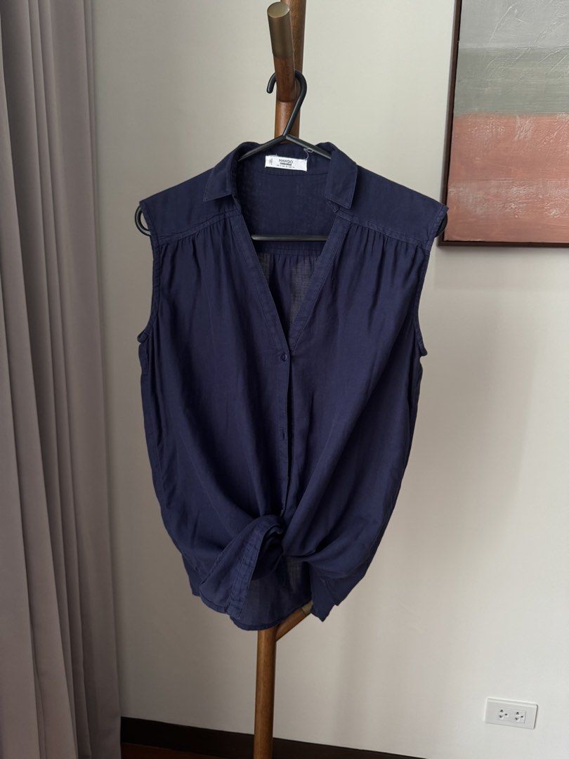 Mango Casualwear Navy Blue Sleeveless Button-Down Blouse (Category: Sleeveless) located in Pasig City. Submitted by kutleyn (Listing ID 1465672491, Image 2). Description: - Brand: Mango - Color: Navy Blue - Size: EUR S / USA XS - Material: Lightweight, breathable fabric - Design: Sleeveless, collar, V-neck, button-down front - Styling: Versatile; wear it loose or tied in a knot at the front - Condition: Great for warm weather and everyday wear.
