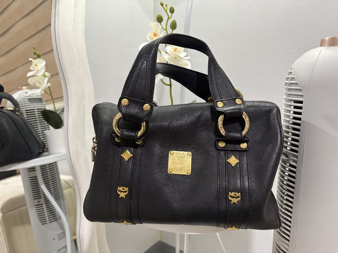 MCM Black Leather Handbag (Category: Luxury Bags & Wallets) located in Quezon City. Submitted by hadescloset (Listing ID 1465734436, Image 1). Description: - Brand: MCM - Material: Premium black pebble leather - Hardware: Gold-tone accents and front logo plaque - Design: Structured shape with vertical strap details and double top handles - Closure: Zip-top closure.