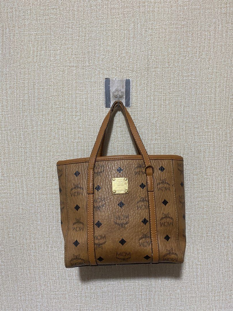 MCM Cognac Visetos Monogram Small Tote Bag (Category: Luxury Bags & Wallets) located in Manila. Submitted by cdb_22 (Listing ID 1465597922, Image 3). Description: - Brand: MCM - Style: Monogram Leather Tote Bag - Color: Brown with tan dual top handles - Hardware: Gold-tone with front metal plaque - Closure: Secure zip-top closure - Interior: Clean, spacious for daily essentials - Condition: Excellent, ready to use.