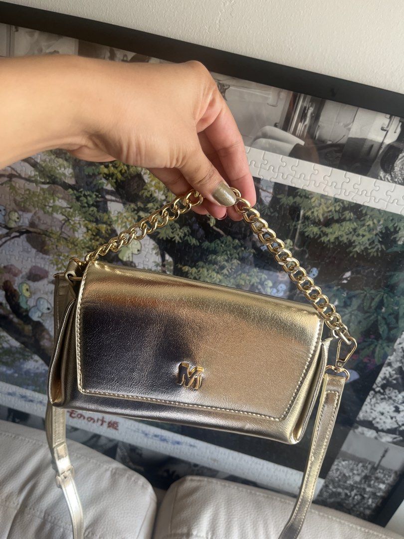 Metallic Gold Shoulder Bag with Chain Handle (Category: Purses & Pouches) located in Pasig City. Submitted by jnzmrq1003 (Listing ID 1465579496, Image 1). Description: - Color/Finish: Shiny metallic gold with a light-catching finish - Hardware: Distinctive 'M' logo on the front flap - Straps: Includes a chunky gold chain top handle and a matching long strap - Closure: Secure flap front closure - Condition: Clean surface, no scuffs seen - not used