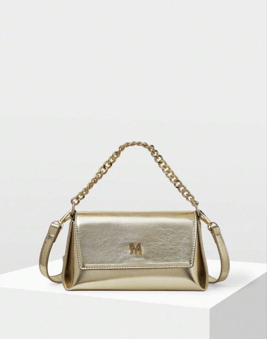 Metallic Gold Shoulder Bag with Chain Handle (Category: Purses & Pouches) located in Pasig City. Submitted by jnzmrq1003 (Listing ID 1465579496, Image 3). Description: - Color/Finish: Shiny metallic gold with a light-catching finish - Hardware: Distinctive 'M' logo on the front flap - Straps: Includes a chunky gold chain top handle and a matching long strap - Closure: Secure flap front closure - Condition: Clean surface, no scuffs seen - not used