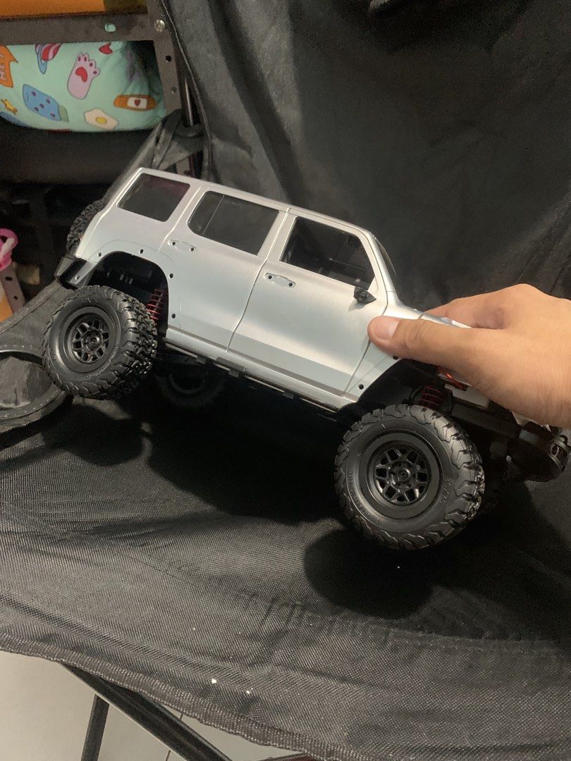 MN300 (Category: Remote Control Toys) located in Mataasnakahoy. Submitted by grailsph.81630 (Listing ID 1465746888, Image 3). Description: - Scale: Silver SUV RC crawler body shell - Interior: Detailed black interior and windows - Wheels: All-terrain tires mounted on black rims - Suspension: Visible red coil springs - Design: Clean silver paint with realistic door handles and sunroof detail - Condition/Use: Ready for custom build or display.