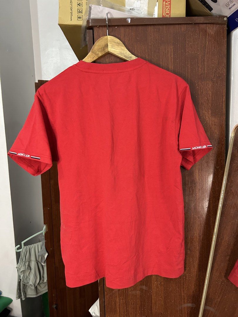 Moncler Red T-Shirt Size S (Category: Tshirts & Polo Shirts ) located in Davao. Submitted by ruggedthrift444 (Listing ID 1465687165, Image 2). Description: Red Moncler cotton t-shirt in size small. Features the classic Moncler logo patch on the chest. Has branded sleeve detailing with tricolor striping on the cuffs. Tag shows Moncler USA Inc. labeling and made in Italy details. Inner neck tag has some yellowing discoloration marks visible..