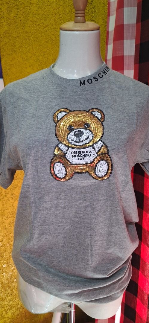 Moschino Grey Sequin Teddy Bear T-Shirt (Category: Shirts) located in Manila. Submitted by katkween23 (Listing ID 1465634075, Image 1). Description: - Brand new with tags (BNWT) - Color: Grey - Material: 100% Cotton - Fit: Regular crew neck, short sleeves - Details: Signature Moschino lettering on the neckline - Design: Eye-catching large sequin teddy bear graphic with 'This is not a Moschino toy' text.