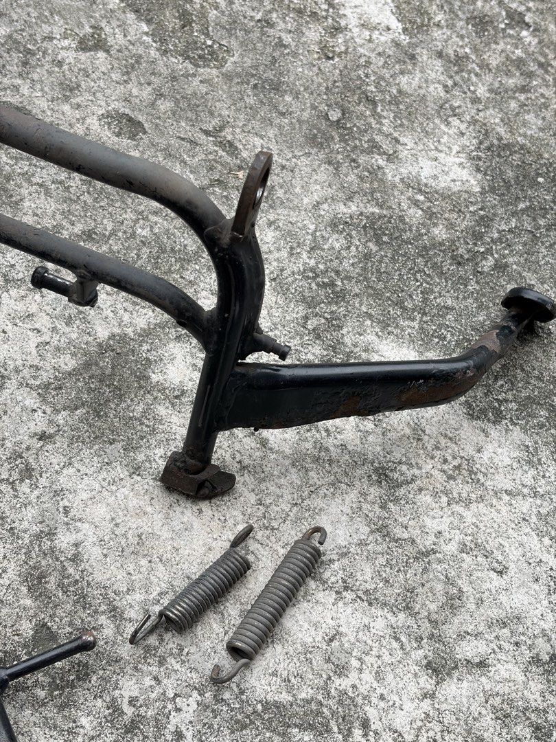 Motorcycle Centre Stand, Side Stand, and Springs (Category: Bicycles) located in Manila. Submitted by finderskeepersmnl_092026 (Listing ID 1465648075, Image 3). Description: - Motorcycle parts bundle ideal for project bikes or budget repairs - Includes: Centre stand, OEM side stand, aftermarket Mokoto adjustable side stand, and 2 tension springs - Condition: Shows visible signs of rust, wear, and previous use - Great as functional spares or repla