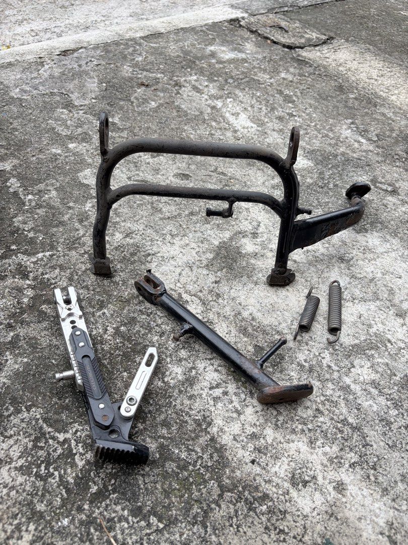 Motorcycle Centre Stand, Side Stand, and Springs (Category: Bicycles) located in Manila. Submitted by finderskeepersmnl_092026 (Listing ID 1465648075, Image 1). Description: - Motorcycle parts bundle ideal for project bikes or budget repairs - Includes: Centre stand, OEM side stand, aftermarket Mokoto adjustable side stand, and 2 tension springs - Condition: Shows visible signs of rust, wear, and previous use - Great as functional spares or repla