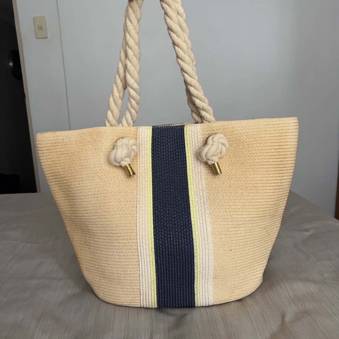 M&S Collection Striped Straw Shopper Bag (Category: Beach Bags) located in Pasig City. Submitted by jenscloset86 (Listing ID 1465636789, Image 2). Description: Mark & Spencer M&S Collection • Straw beach tote bag in beige with dark blue and yellow center stripe. • Thick twisted rope handles with knotted ends and gold-tone metal hardware. • Vibrant yellow fabric lining with internal slip pockets and a zippered pocket. • Liquid stain inside but not