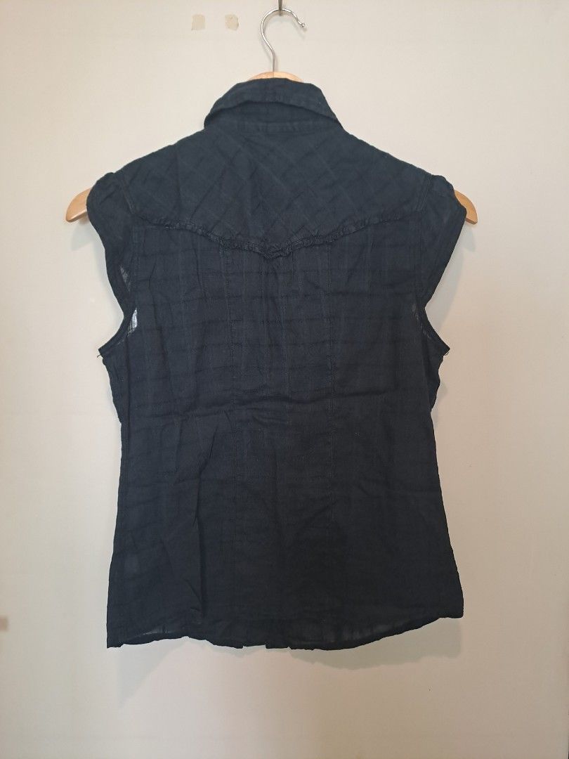 MUDD Black sleeveless (Category: Blouses) located in Manila. Submitted by joanbalde39643 (Listing ID 1465668994, Image 2). Description: The item pictured is a Mudd sleeveless button-down top featuring a distinct Western style design. It is constructed with classic single-point pointed front yokes, dual button-flap chest pockets, a subtle plaid pattern textured into the dark fabric, and a traditional button-up placket running down the front..