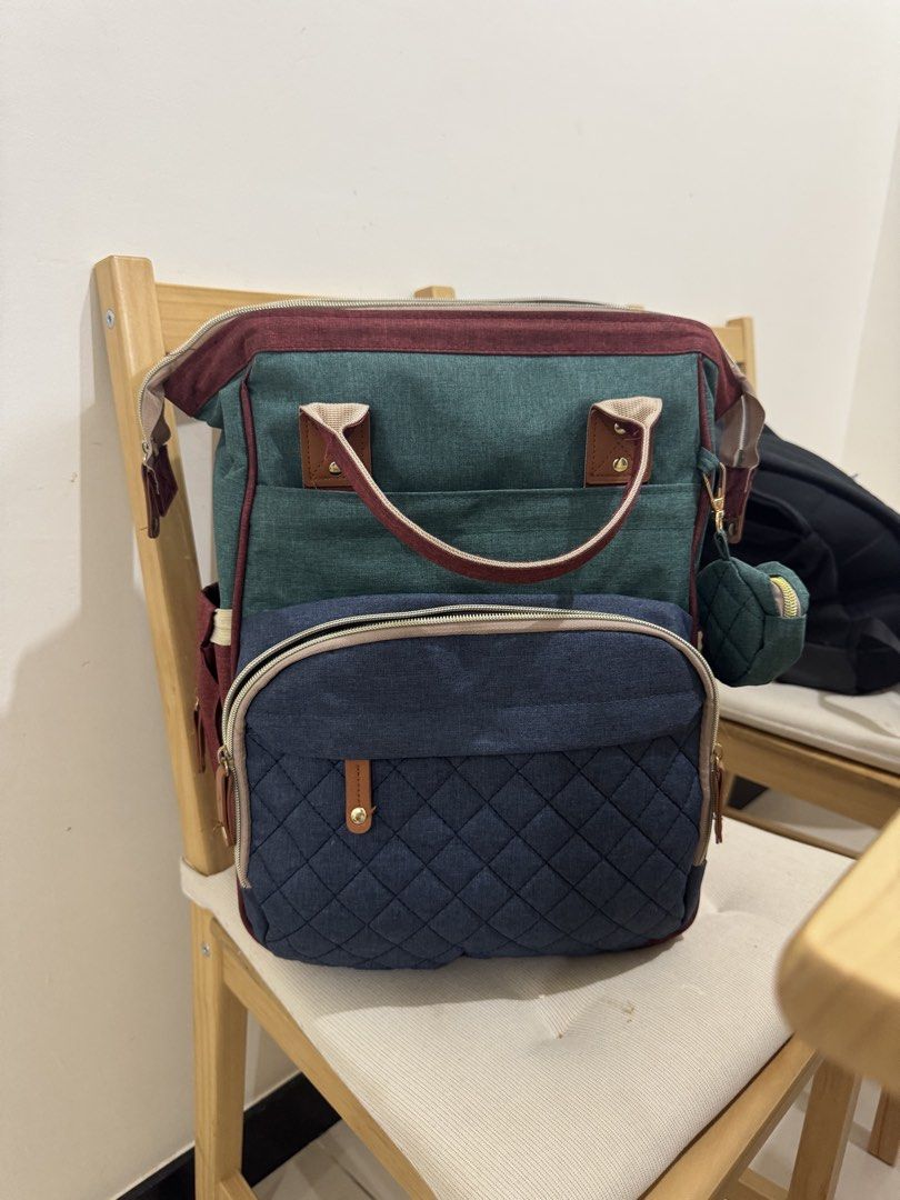 Multicolor Canvas Diaper Backpack with Small Pouch (Category: Diaper Bags & Wetbags) located in Mandaluyong City. Submitted by fidgetcracker (Listing ID 1465712799, Image 1). Description: - Multi-tone diaper backpack in green, blue, and burgundy canvas - Quilted blue front zip pocket for quick-access items - Spacious main compartment with smooth gold-toned zippers - Sturdy top handles and stylish brown leatherette accents - Includes a matching mi