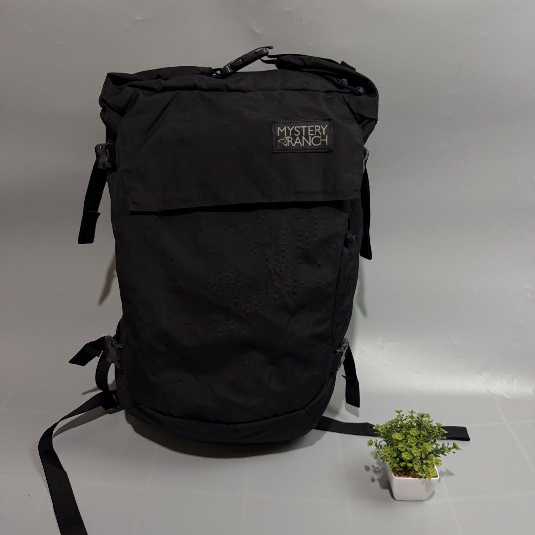 Mystery Ranch Black Backpack (Category: Backpacks) located in Bago City. Submitted by g___shop (Listing ID 1465689329, Image 1). Description: - Brand: Mystery Ranch - Color: Classic Black - Material: Clean, durable canvas - Closure: Secure roll-top with buckle - Comfort: Padded mesh shoulder straps - Fit: Multiple adjustment straps on sides and back - Branding: Signature logo patch on front flap - Condition: Excellent/Ready to use - Mode of Payme
