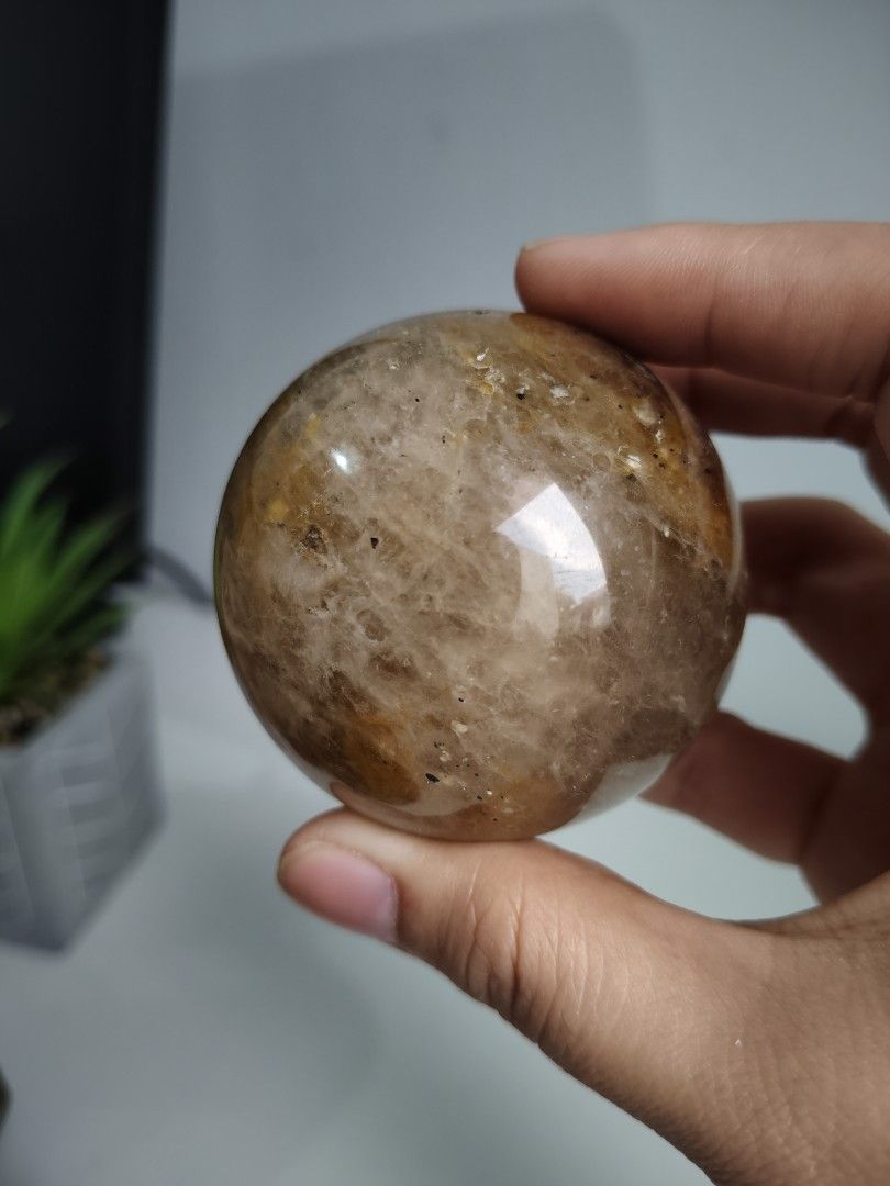 Golden Healer Crystal Sphere (Category: Precious Stones) located in Cavite. Submitted by lynlcb (Listing ID 1465654421, Image 1). Description: - High-gloss polished round quartz crystal sphere - Warm golden brown and orange interior with dark mineral inclusions - weigt is - Solid, satisfying weight that fits nicely in the palm - Flawless smooth finish with no chips or scratches - Ideal statement piece for your desk or shelf display - weight is 29