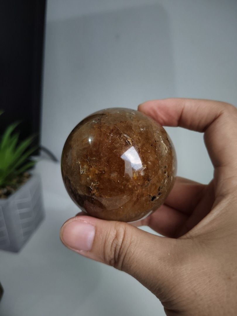 Golden Healer Crystal Sphere (Category: Precious Stones) located in Cavite. Submitted by lynlcb (Listing ID 1465654421, Image 3). Description: - High-gloss polished round quartz crystal sphere - Warm golden brown and orange interior with dark mineral inclusions - weigt is - Solid, satisfying weight that fits nicely in the palm - Flawless smooth finish with no chips or scratches - Ideal statement piece for your desk or shelf display - weight is 29
