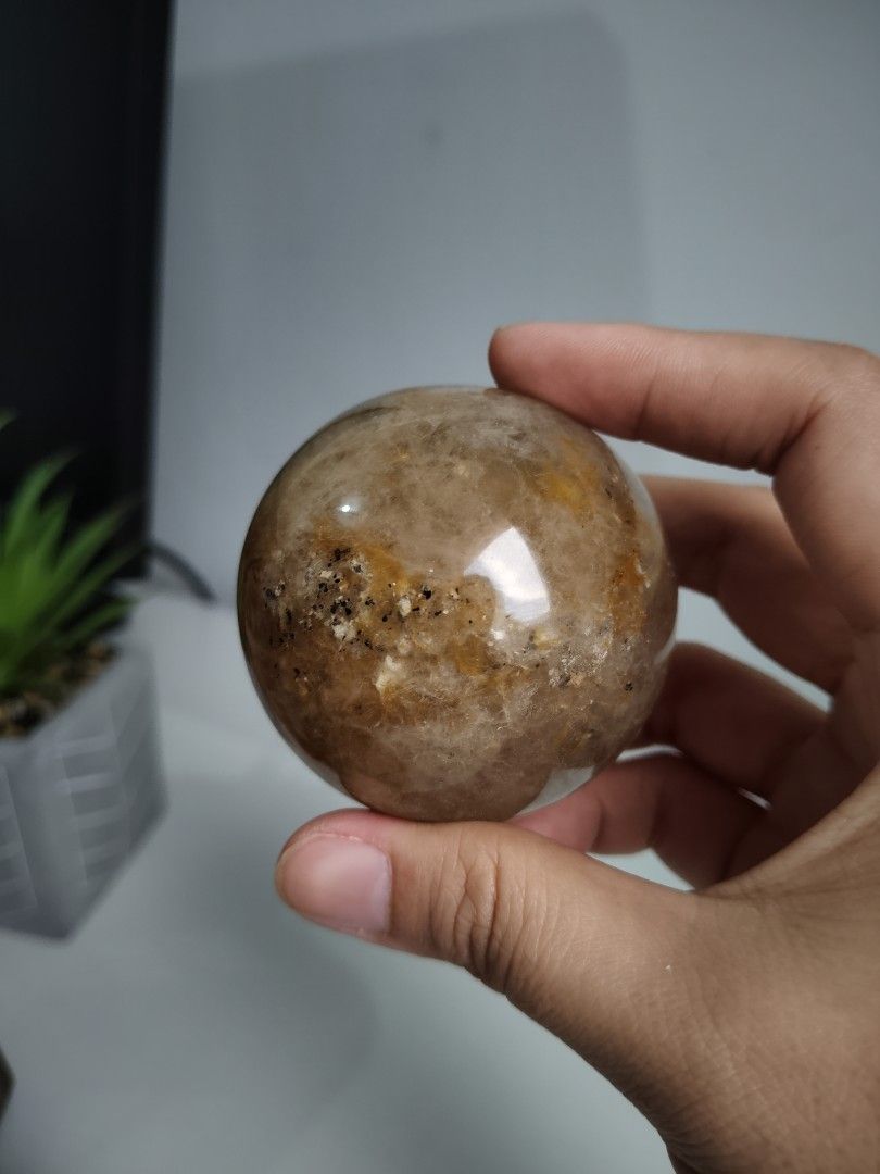 Golden Healer Crystal Sphere (Category: Precious Stones) located in Cavite. Submitted by lynlcb (Listing ID 1465654421, Image 2). Description: - High-gloss polished round quartz crystal sphere - Warm golden brown and orange interior with dark mineral inclusions - weigt is - Solid, satisfying weight that fits nicely in the palm - Flawless smooth finish with no chips or scratches - Ideal statement piece for your desk or shelf display - weight is 29
