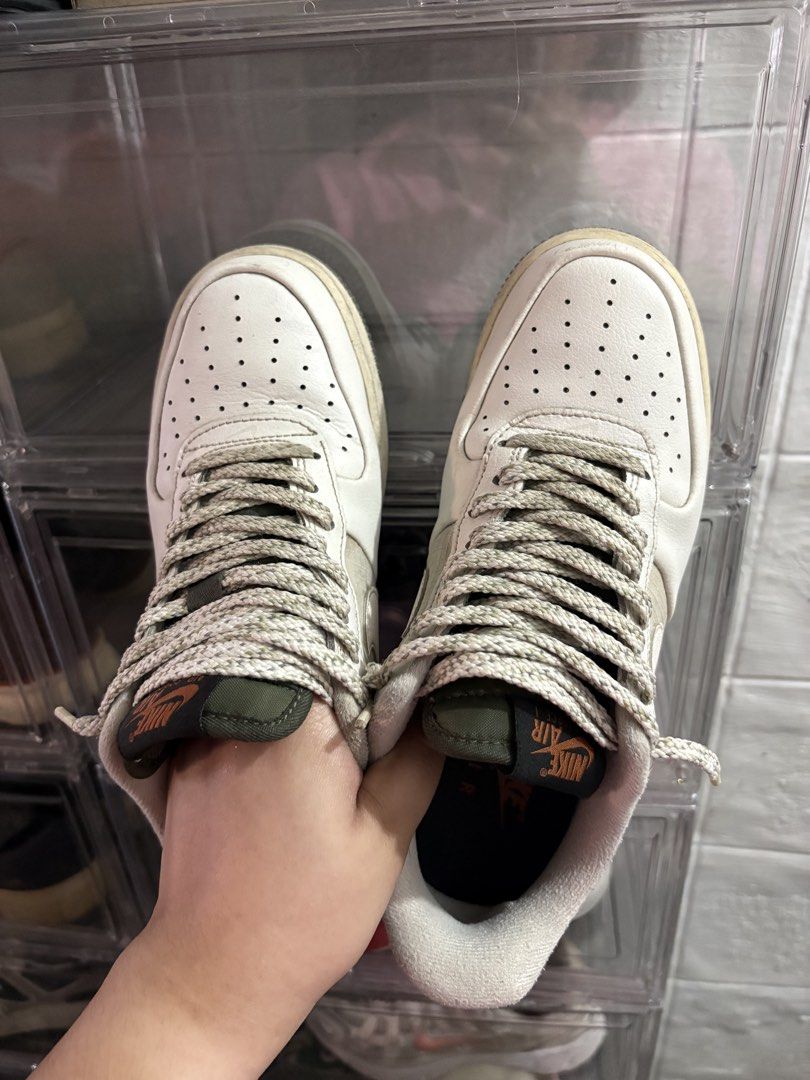 Nike Air Force 1 Sneakers (Category: Casual Shoes) located in Manila. Submitted by bern_salamanca (Listing ID 1465587401, Image 2). Description: - Model: Nike Air Force 1 • Size: US 7.5 / UK 6.5 / EUR 40.5 • Color: Sail/Cream • Condition: Pre-loved / gently used - Colorway: White with olive green tongue and orange Nike Air branding - Unique Details: Grid pattern side panels, textured patterned laces, and speckled dark rubber outsoles - Origin: Ma
