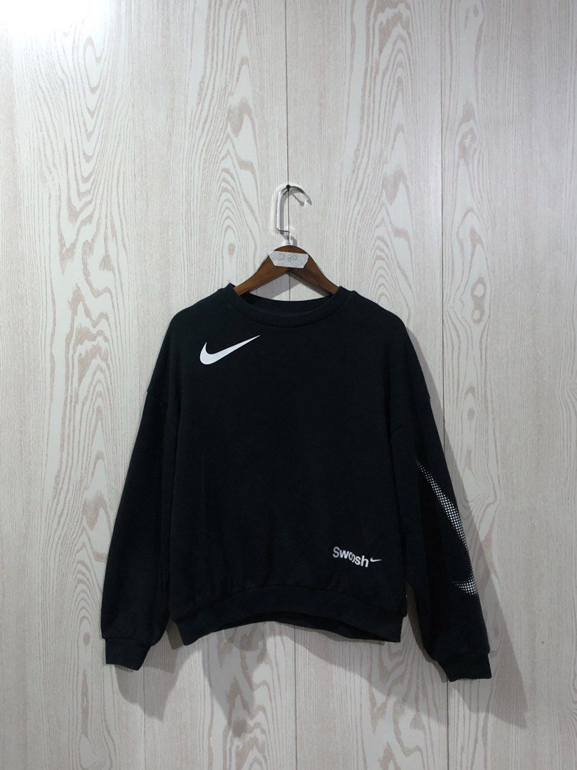 Nike Black Swoosh Sweatshirt (Category: Coats, Jackets and Outerwear) located in Magsaysay. Submitted by ryns_thrifting (Listing ID 1465708241, Image 1). Description: - Brand: Nike - Color: Black with white branding - Design: White swoosh on front right chest, swoosh text near bottom hem, and graphic on left sleeve - Style: Classic crewneck - Size: Neck tag says L, inner tag says M - Material: Comfortable cotton blend - Condition: Great for casua