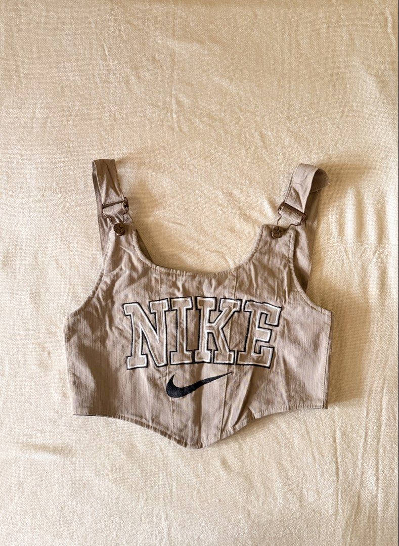 Nike Tan Denim Corset Crop Top (Category: Sleeveless) located in Iloilo. Submitted by hellodindi (Listing ID 1465680328, Image 1). Description: - Brand: Nike - Item: Tan denim corset crop top - Size: Best fits S-M - Details: Large embroidered NIKE lettering with swoosh, adjustable metal-buckled straps with star buttons, and dark lace-up back.