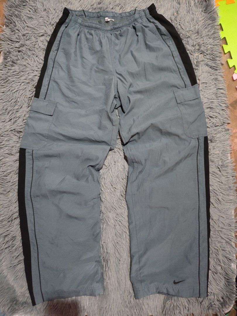 Nike Vintage Grey Cargo Parachute Pants (Category: Joggers) located in Manila. Submitted by mommyregsthriftclothes (Listing ID 1465635229, Image 1). Description: - Brand: Nike - Style: Grey cargo pants with black side panels and piped detailing - Pockets: Side pockets and functional cargo pockets on both legs - Branding: Small embroidered black Nike swoosh near the bottom cuff - Fit/Measurements: Elastic waistband, measures roughly 15" flat acros