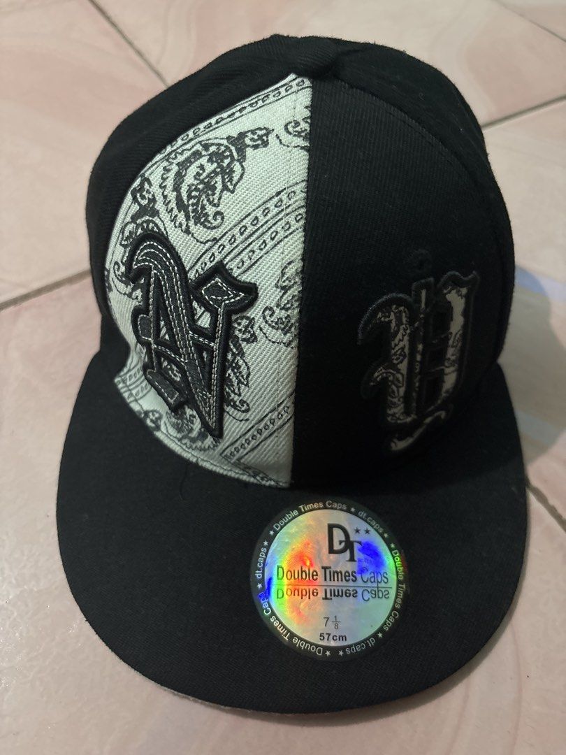 NYC Caps Black and White Snapback Hat Size 7 1/8 (Category: Caps & Hats) located in Binan City. Submitted by fashion_claims (Listing ID 1465582997, Image 1). Description: - Brand: Double Times Caps - Style: Snapback hat with unique split design (Solid black & white paisley bandana pattern) - Details: Embroidered old English front graphics and New York Yankees logo on the back - Brim: Flat brim with original holographic sticker - Size: 7 1/8 (57 c
