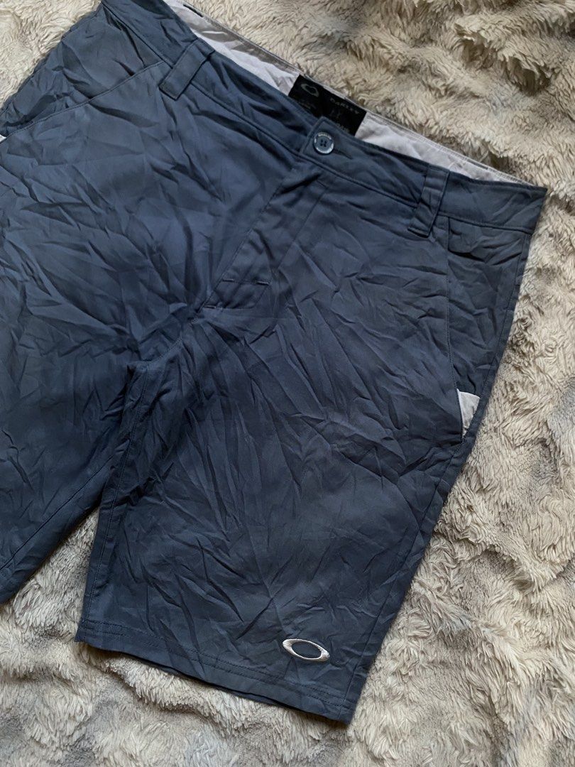 Oakley Gray Athletic Shorts (Category: Shorts) located in Andop. Submitted by safewater-895a (Listing ID 1465677313, Image 2). Description: - Brand: Oakley - Color: Gray - Closure: Button closure with belt loops - Logo: Embroidered ellipse logo on the left leg - Pockets: Two back welt pockets with white accent trim - Details: Oakley brand tag on rear waistband, clean stitching - Condition: Excellent, lightweight and durable for outdoor or casual 