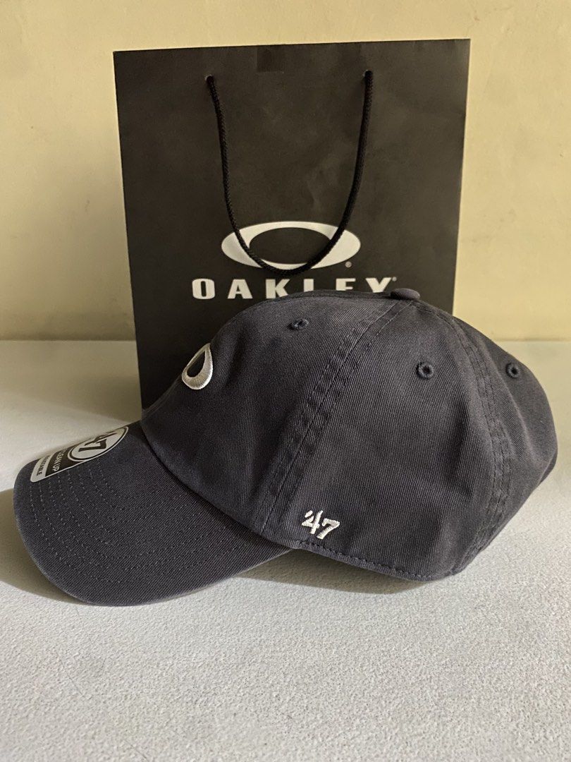 Oakley x '47 Clean Up Adjustable Hat Charcoal Grey 1k ( Decluttering ) (Category: Caps & Hats) located in Quezon City. Submitted by joelds (Listing ID 1465637732, Image 2). Description: - Brand: Oakley x '47 Clean Up collection - Color: Charcoal grey - Design: Embroidered iconic oval ellipse logo on front, '47 branding on side - Fit: Adjustable strapback closure - Brim: Curved brim with original sticker still attached - Condition: Excellent, clea