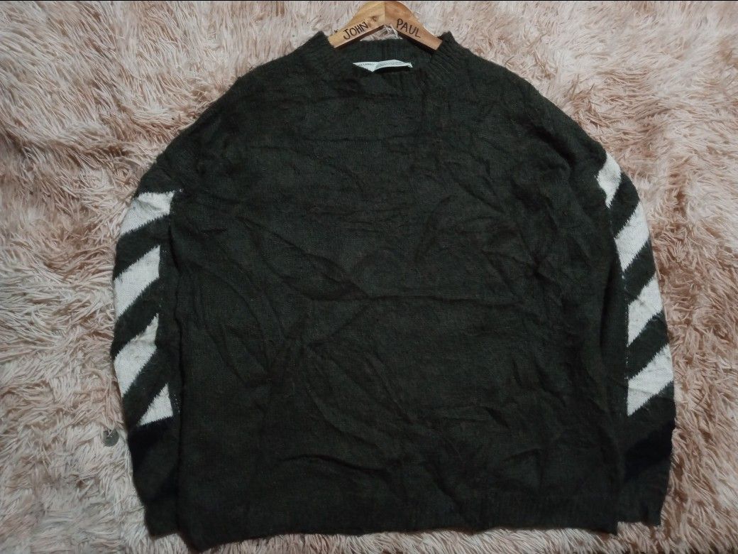 Off-White c/o Virgil Abloh Green Knit Sweater (Category: Coats, Jackets and Outerwear) located in Boston. Submitted by johnpaulvi30029 (Listing ID 1465692631, Image 2). Description: - Brand: Off-White c/o Virgil Abloh - Color: Dark green with signature white graphics - Design: Large back arrow graphic and diagonal sleeve stripes - Details: Classic ribbed collar, cuffs, and hem with 2013 copyright neck label - Fit & Material: Relaxed fit, thick kn