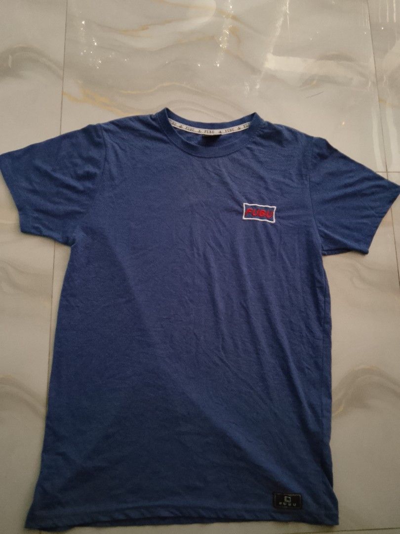 Orig FUBU Blue Shirts (Category: Tshirts & Polo Shirts ) located in Manila. Submitted by wildwater26 (Listing ID 1465645692, Image 1). Description: - Brand: FUBU - Color: Blue - Material: 100% cotton, made in Bangladesh - Design: Regular crew neck with chest pocket and small embroidered logo - Details: Branded inner neckline tape - Condition/Style: Classic hip-hop heritage piece, perfect for comfortable everyday casual wear.