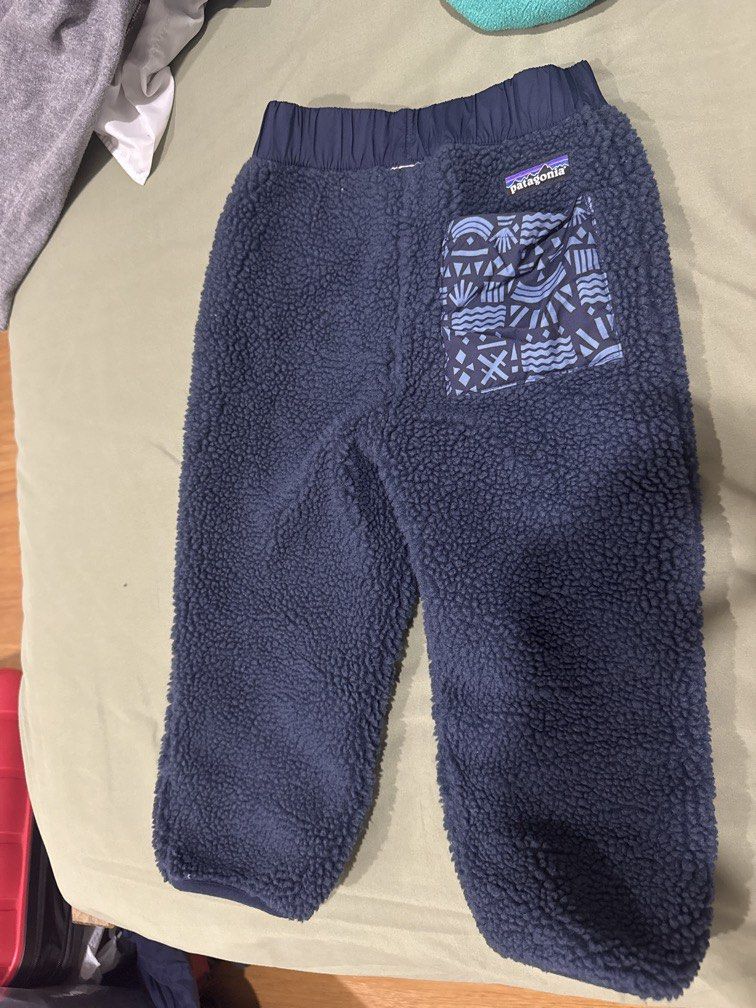 Patagonia Reversible Fleece and Printed Pants (Category: Babies & Kids Fashion) located in Manila. Submitted by .famousamos (Listing ID 1465692575, Image 2). Description: Patagonia pants, reversible design. One side has fuzzy navy blue fleece. Other side features a dark blue geometric pattern with abstract shapes. Elastic waistband and stretchy cuffs at the ankles. Includes a small pocket on the back with a snap button closure and Patagonia logo 
