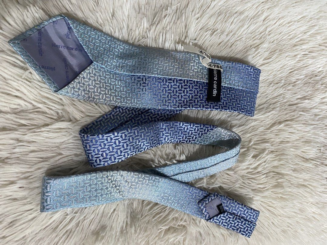 Pierre Cardin Blue Geometric Silk Necktie (Category: Ties) located in Bulacan. Submitted by rich2545 (Listing ID 1465581475, Image 2). Description: - Brand: Pierre Cardin - Color: Shades of blue with a subtle light-to-dark gradient - Design: Geometric patterned weave - Details: Branded lining and keeper loop on the back - Condition: Brand new, clean fabric with tag still attached.