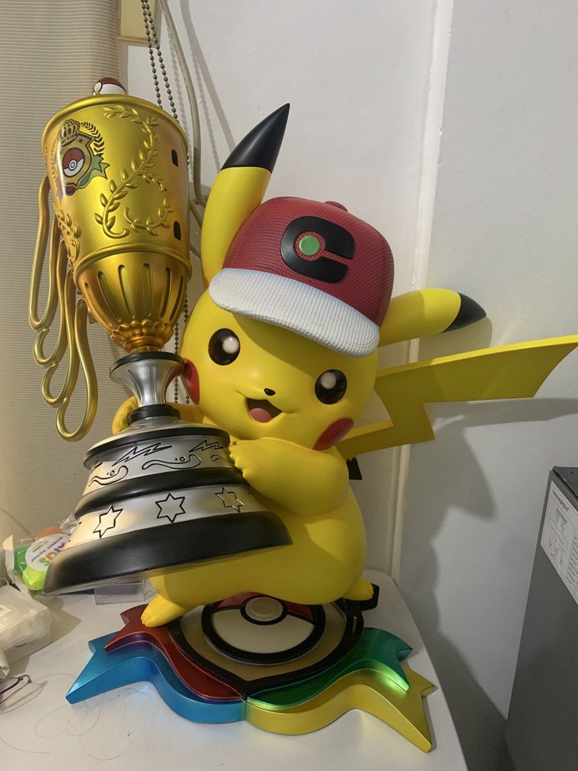 Pikachu World Champion Figure (Category: Figurines & Statues) located in Manila. Submitted by bearsncuddlesph (Listing ID 1465627140, Image 1). Description: - Large Pikachu figure holding a big gold trophy - Wears the iconic red and white cap with green symbol - Detailed Pokeball and multi-color ribbon base - Vibrant yellow body with signature black-tipped ears - Stands firmly on its base, perfect for display - Great collectible piece for Pokemon