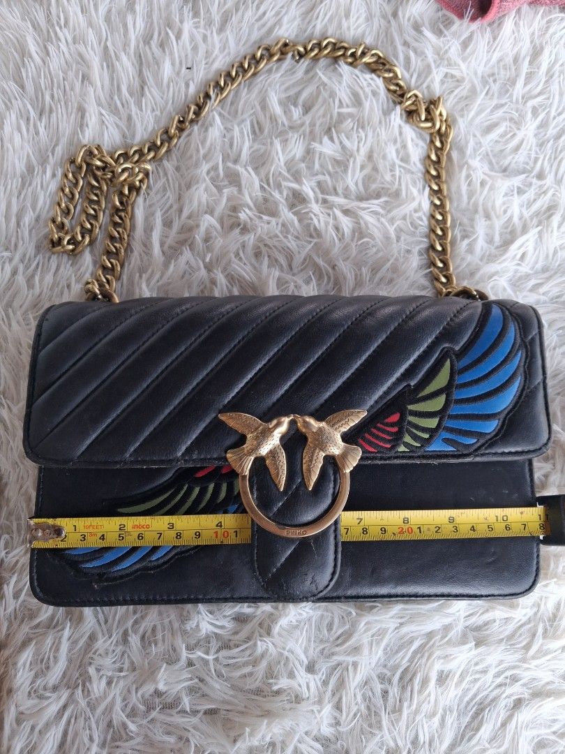Pinko Black Leather Love Bag with Chain Strap (Category: Luxury Bags & Wallets) located in Agoncillo. Submitted by vinsoy07 (Listing ID 1465662821, Image 2). Description: - Pinko crossbody bag in black leather with chevron quilting - Features iconic gold metal Love Birds buckle on the front flap - Unique and colorful embroidered wing details on the sides - Compact dimensions: approx. 20 cm x 10 cm - Stylish chunky gold chain shoulder strap - Prac