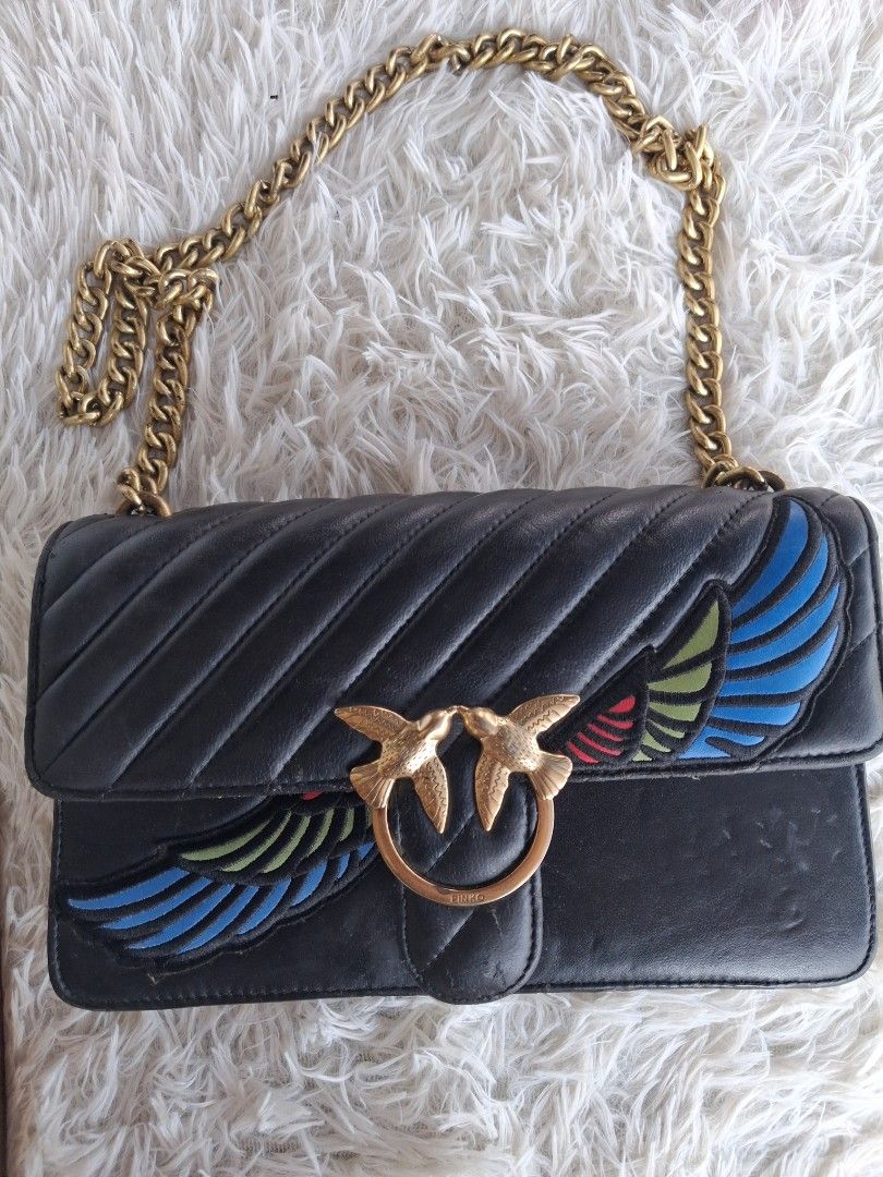 Pinko Black Leather Love Bag with Chain Strap (Category: Luxury Bags & Wallets) located in Agoncillo. Submitted by vinsoy07 (Listing ID 1465662821, Image 1). Description: - Pinko crossbody bag in black leather with chevron quilting - Features iconic gold metal Love Birds buckle on the front flap - Unique and colorful embroidered wing details on the sides - Compact dimensions: approx. 20 cm x 10 cm - Stylish chunky gold chain shoulder strap - Prac