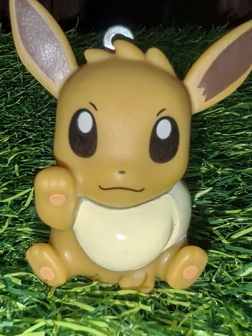 Pokémon Eevee PVC Figurine Keychain Charm (Category: Character Goods) located in Paranaque City. Submitted by furugiyafinds (Listing ID 1465670612, Image 2). Description: - Official Pokémon merchandise with stamped logo on the back - Adorable Eevee sitting pose with one raised paw - Classic brown body with cream chest tuft and tail tip - Equipped with a sturdy metal loop attachment on top - Lightweight hollow base design - Perfect for keys, bags,