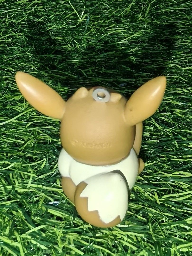 Pokémon Eevee PVC Figurine Keychain Charm (Category: Character Goods) located in Paranaque City. Submitted by furugiyafinds (Listing ID 1465670612, Image 3). Description: - Official Pokémon merchandise with stamped logo on the back - Adorable Eevee sitting pose with one raised paw - Classic brown body with cream chest tuft and tail tip - Equipped with a sturdy metal loop attachment on top - Lightweight hollow base design - Perfect for keys, bags,