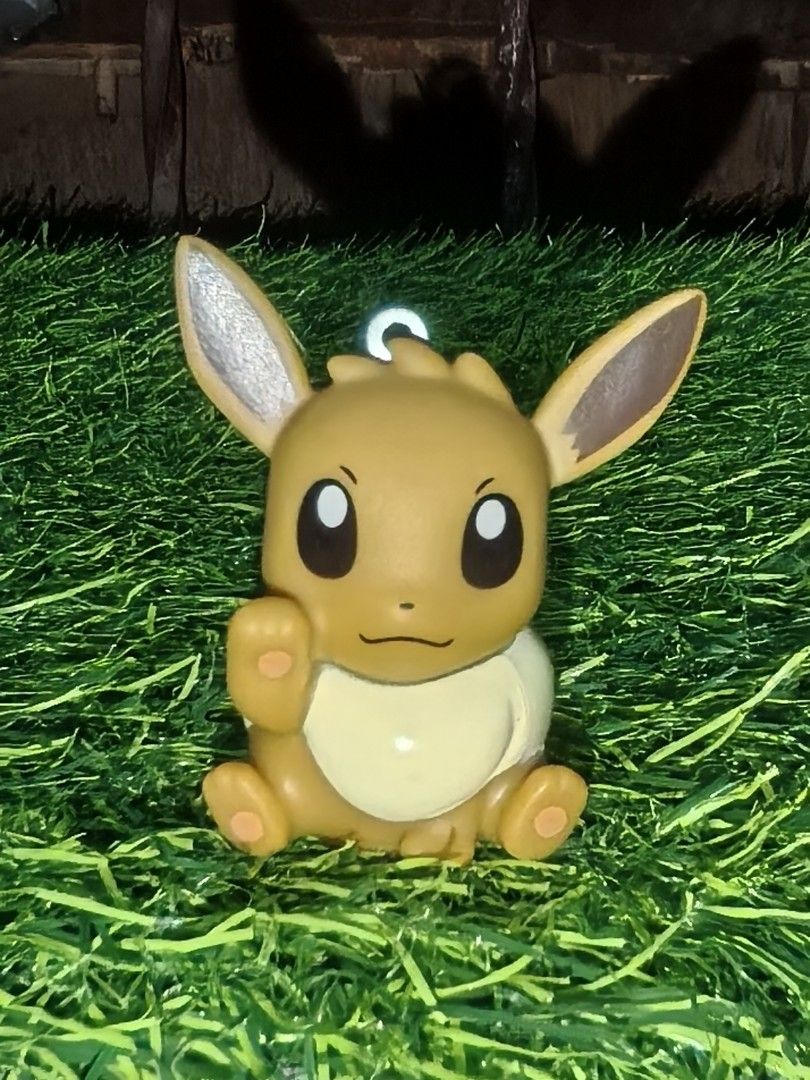Pokémon Eevee PVC Figurine Keychain Charm (Category: Character Goods) located in Paranaque City. Submitted by furugiyafinds (Listing ID 1465670612, Image 1). Description: - Official Pokémon merchandise with stamped logo on the back - Adorable Eevee sitting pose with one raised paw - Classic brown body with cream chest tuft and tail tip - Equipped with a sturdy metal loop attachment on top - Lightweight hollow base design - Perfect for keys, bags,