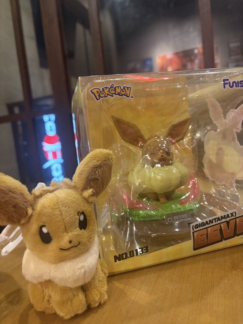 Pokémon Gigantamax Eevee Figure (No. 0133) (Category: Figurines & Statues) located in Manila. Submitted by laurencebe89435 (Listing ID 1465693935, Image 1). Description: Pokémon Gigantamax Eevee figure inside original box, plus a small Eevee plushie sitting next to it. Box shows Eevee winking with big fluffy neck ruff. Packaging plastic still intact. Great collectible piece for Pokémon fans. Displayed briefly on a shelf, box kept in storage..