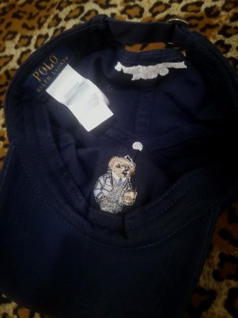 Polo Ralph Lauren Bear Navy Baseball Cap (Category: Caps & Hats) located in Cebu City. Submitted by roadthrift (Listing ID 1465702987, Image 3). Description: - Brand: Polo Ralph Lauren - Color: Navy Blue - Design: Iconic Polo Bear holding a football embroidered on front with 'POLO' lettering - Back Details: 'POLO RALPH LAUREN' embroidered across the strap area - Material: 100% cotton - Size: One size fits most (tagged 59cm), adjustable metal buck