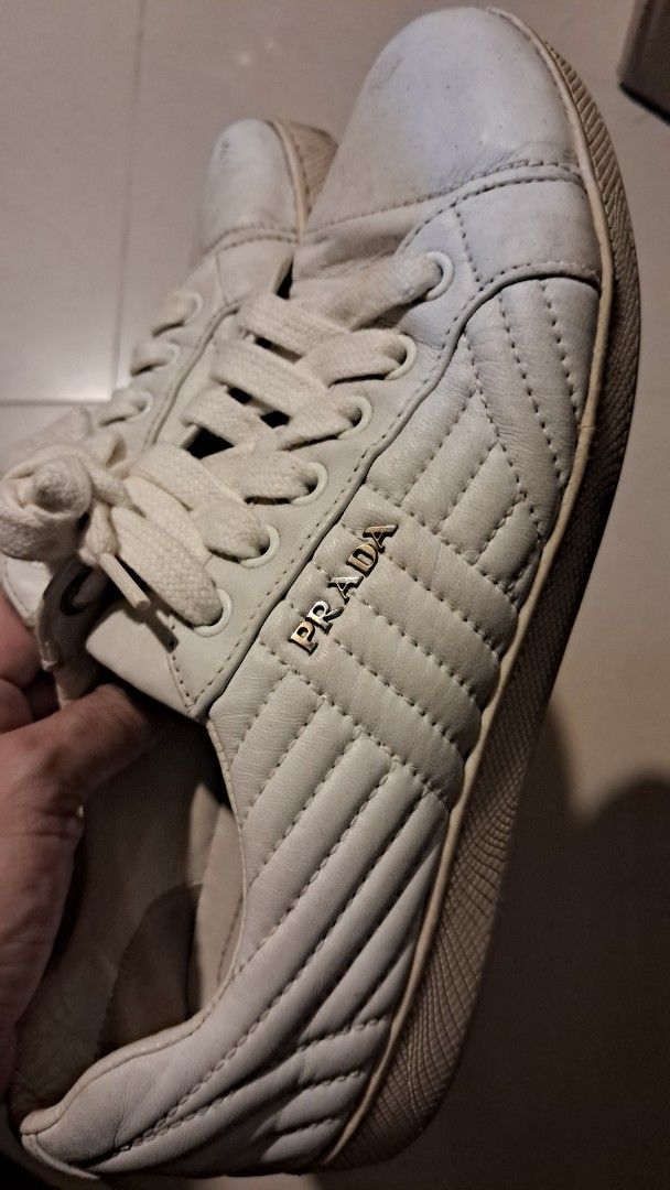 Prada Quilted White Leather Sneakers Size 36.5 (Category: Sneakers) located in Cavite. Submitted by naning049 (Listing ID 1465580681, Image 2). Description: - Brand: Prada - Style: Quilted leather sneakers with metal side logo - Color: White with flat white laces - Size: EU 36.5 - Origin: Made in Italy - Condition: Pre-loved; has visible scuffs on toe caps, wear on soles and inner lining, and a small crack on the rubber outsole near the toe - Per