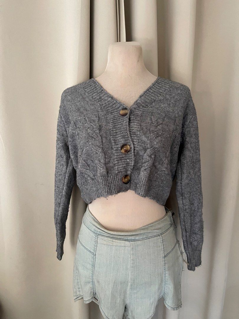 premium Grey Cable Knit Cropped Button Cardigan (Category: Coats, Jackets and Outerwear) located in Cainta. Submitted by zlove111 (Listing ID 1465758076, Image 1). Description: - Style: Cropped cable knit cardigan - Color: Grey with brown buttons - Neckline: V-neck - Details: Ribbed cuffs, hem, and neckline - Fit: Cozy knit fabric, ideal for layering over high-waisted bottoms.