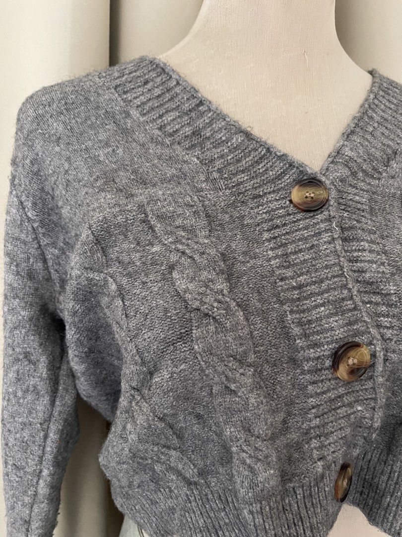 premium Grey Cable Knit Cropped Button Cardigan (Category: Coats, Jackets and Outerwear) located in Cainta. Submitted by zlove111 (Listing ID 1465758076, Image 2). Description: - Style: Cropped cable knit cardigan - Color: Grey with brown buttons - Neckline: V-neck - Details: Ribbed cuffs, hem, and neckline - Fit: Cozy knit fabric, ideal for layering over high-waisted bottoms.