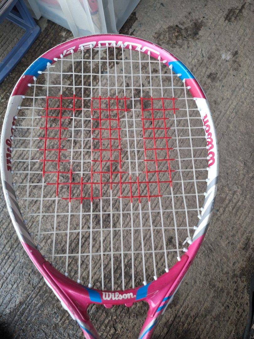Racket for tennis (Category: Racket and Ball Sports) located in Manila. Submitted by rocksolid227 (Listing ID 1465618959, Image 3). Description: - Item: Wilson tennis racket - Color: Pink, white, and blue accents with a black grip - Perfect for tennis practice or recreational play .