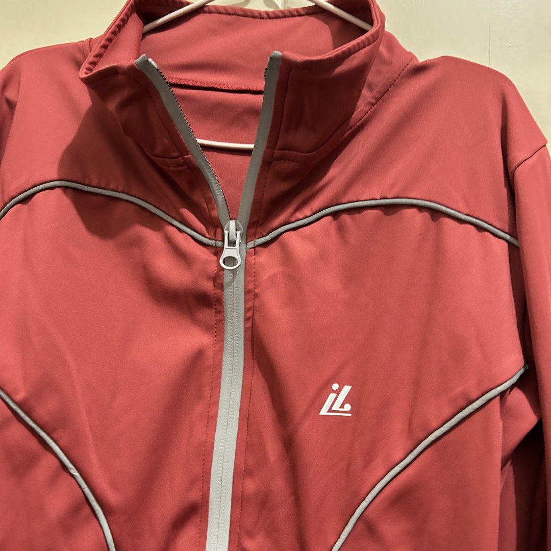 Red Athletic Zip-Up Jacket with Thumbholes (Category: Activewear) located in Manila. Submitted by frances_001 (Listing ID 1465691920, Image 3). Description: - Color: Red with grey piping and white logo - Size: Medium (M) - Fit: Fitted waist with curved seam details - Features: Stand-up collar, full front zip, and long sleeves with thumbhole cuffs - Material: Smooth, stretchy athletic fabric.